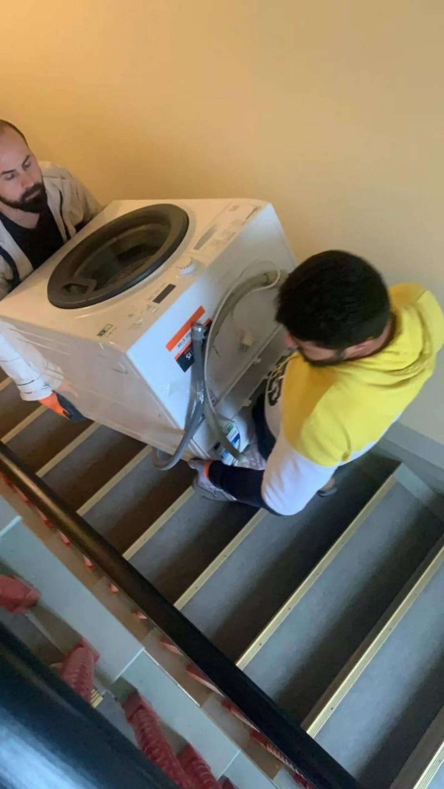 Umzugshelfer trägt einen Karton durch ein enges Altbau-Treppenhaus in Berlin